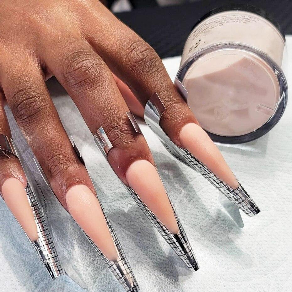 Processo de construção de um alongamento de unhas, no modelo acrílico. Unhas em formato stiletto e com os moldes durante o processo.